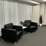 Right_Path_RecoveryRio_IOP04 copy - Right Path Recovery San Diego - Right Path Recovery San Diego Two black leather armchairs with a small white side table and a potted plant between them in a modern office waiting area.