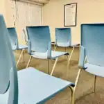 Right_Path_RecoveryRio_IOP30 - Right Path Recovery San Diego - Right Path Recovery San Diego Empty room with light blue chairs arranged in rows and a framed poster on the wall.",